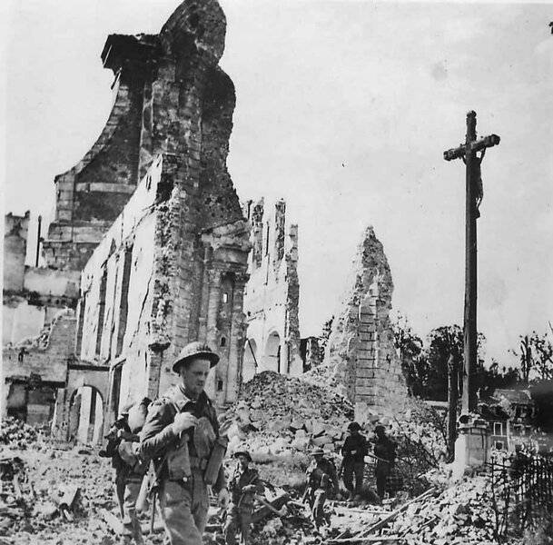British_soldiers_pass_ruins_of_St_Desir_Church_in_Lisieux_Normandy.jpg